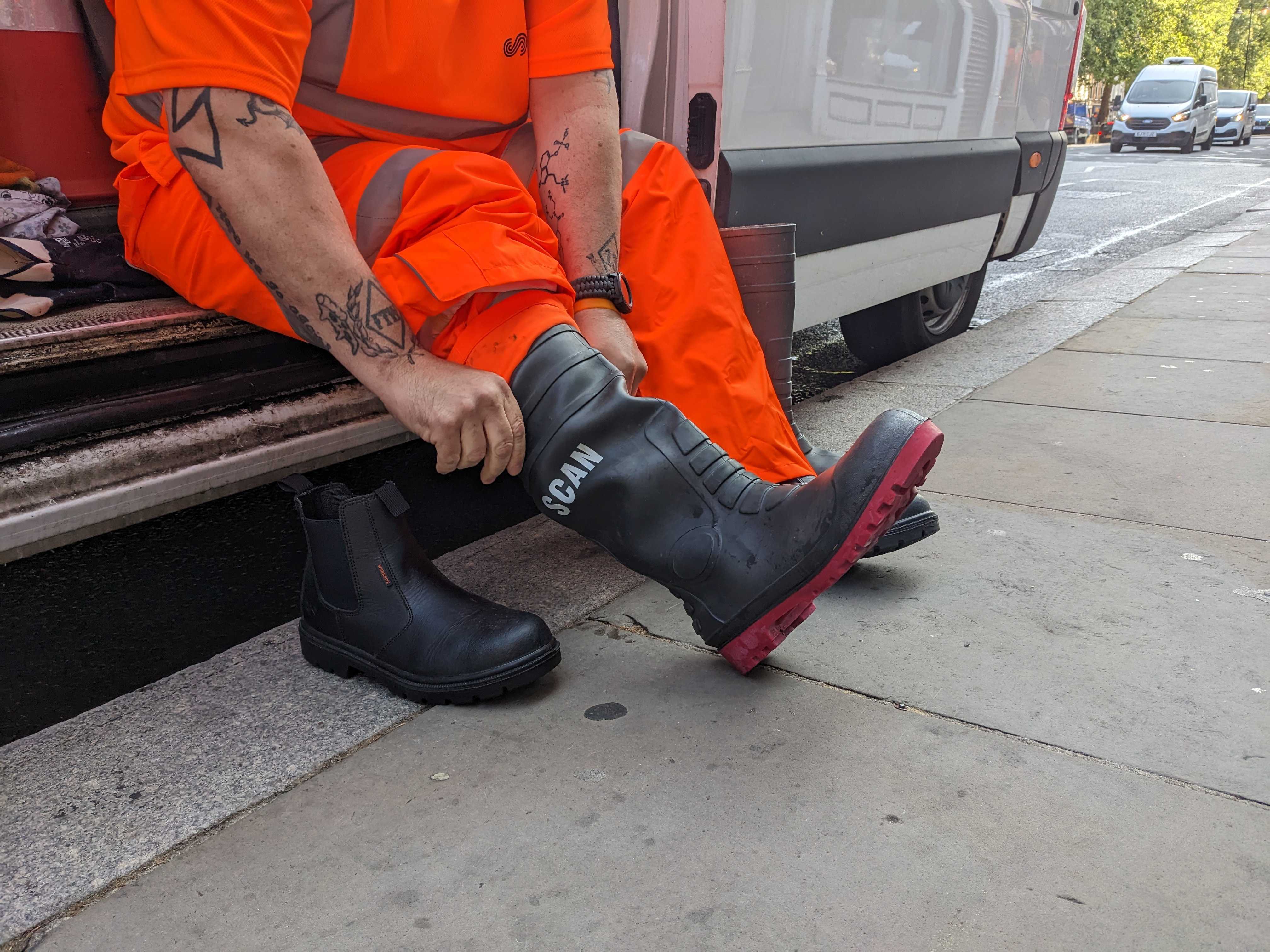 A member of the grime busters street cleaning team sat in a van butting on wellington boots ahead of starting work