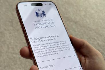 A hand holding a smartphone displaying the Kensington and Chelsea Council e-newsletters sign-up page