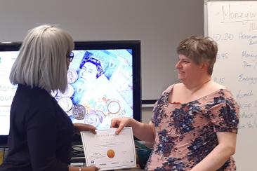 Resident receiving a certificate at the end of a Money Wise course