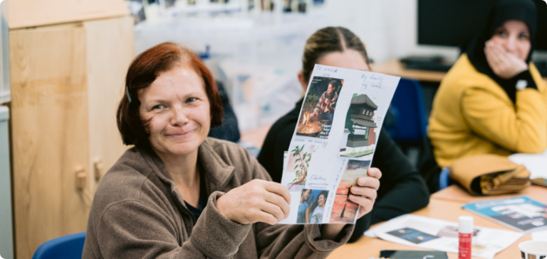 Woman holding up her work and smiling during a community adult learning class