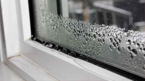A double-glazed window with water droplets building up on the bottom of the glass