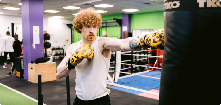 Man training with boxing gloves and punching a bag in a gym