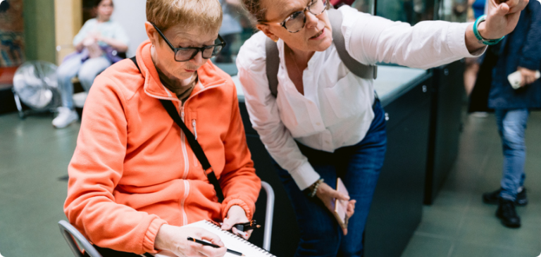 Two women in discussion while one takes notes during a class