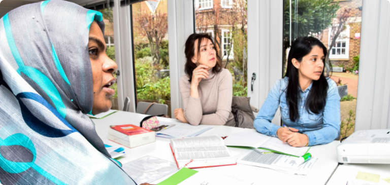 Women studying together at a table with books and papers